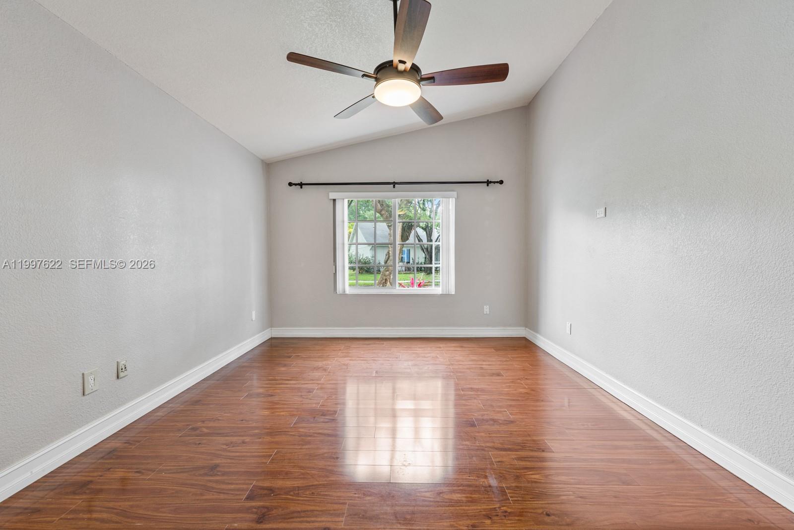 14912 Southwest 143rd Court, Unit 14912 Miami, FL 33186 - Photo 20 of 35 an empty room with wooden floor chandelier fan and windows
