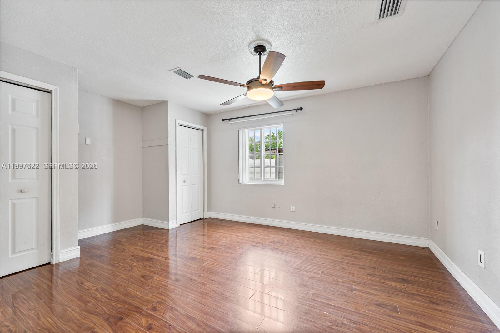 14912 Southwest 143rd Court, Unit 14912 Miami, FL 33186 - Photo 26 of 35 a view of an empty room with wooden floor and a window