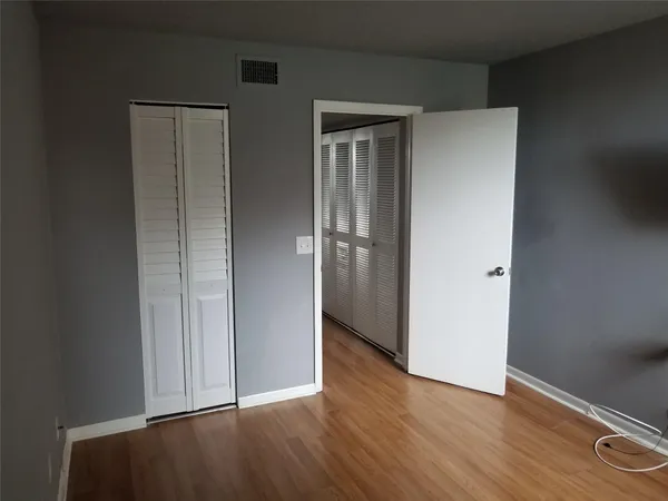 an empty room with wooden floor & closet and windows