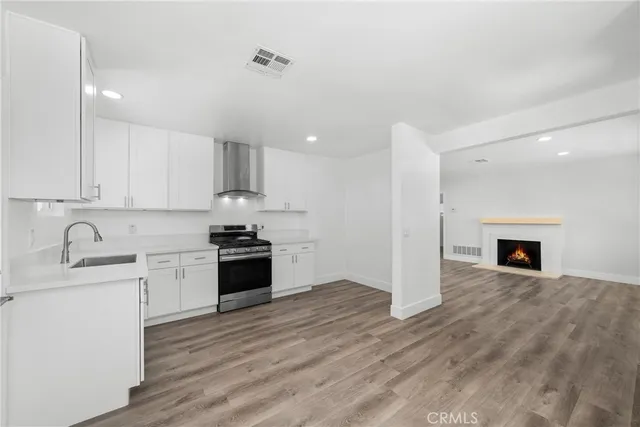 a large kitchen with granite countertop a stove top oven a sink dishwasher and a fireplace with wooden floor