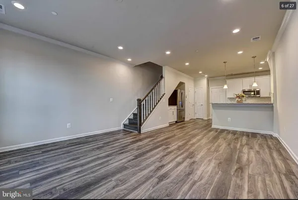 a view of empty room with wooden floor and kitchen