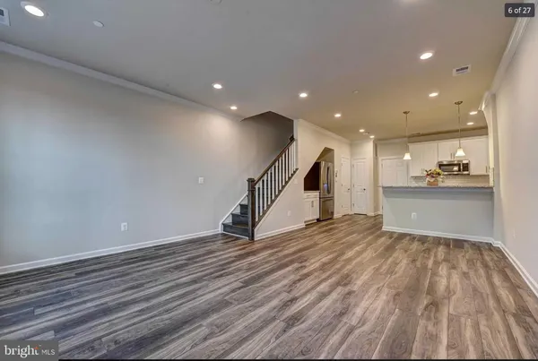 a view of empty room with wooden floor and kitchen