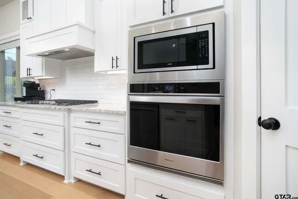 a kitchen with stainless steel appliances white cabinets a stove and a microwave