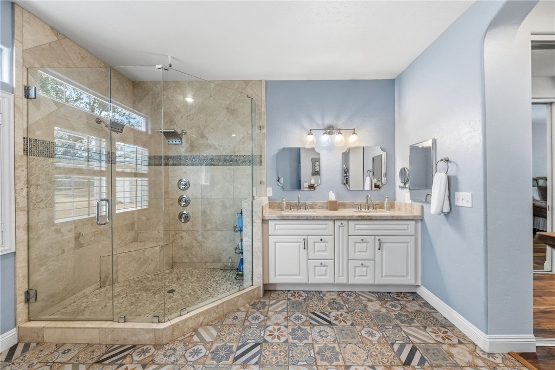 45600 La Cruz Drive Temecula, CA 92590 - Photo 49 of 75 a bathroom with a granite countertop sink a mirror and a shower