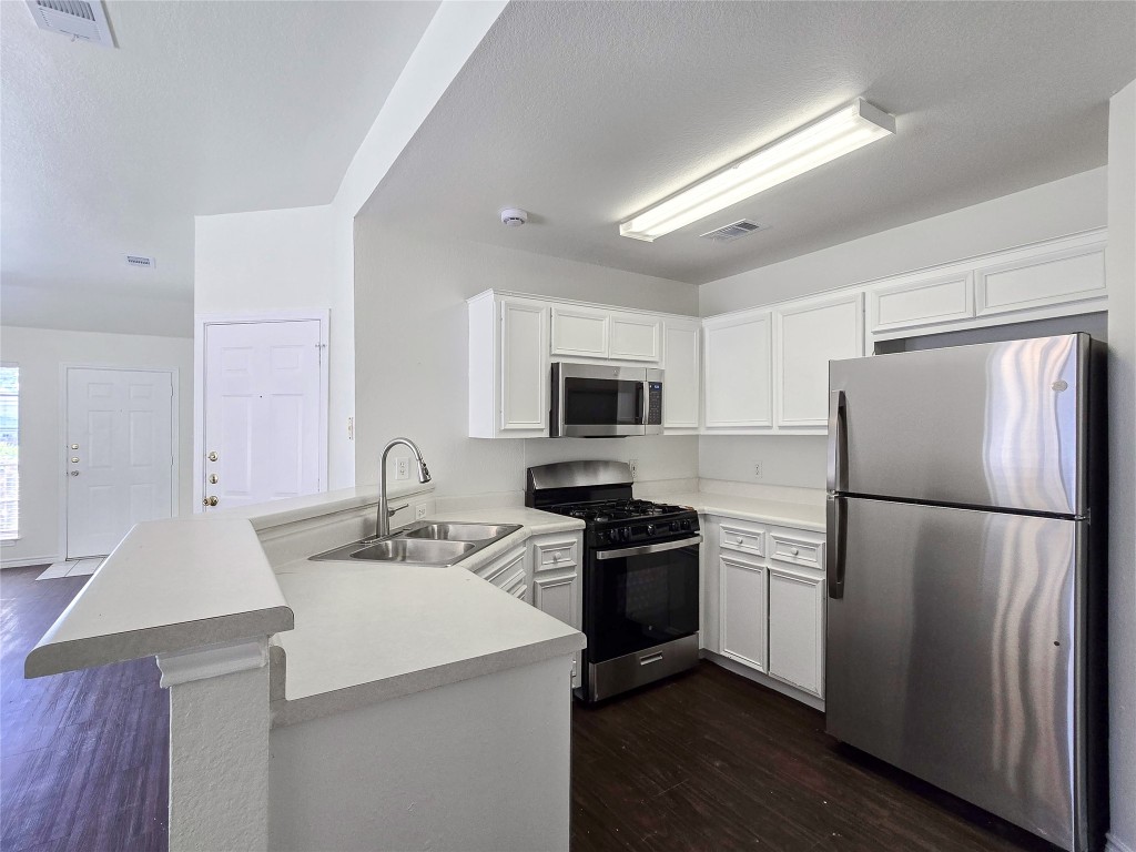 300 Tamara Drive, Unit B Georgetown, TX 78628 - Photo 8 of 16 a kitchen with a sink a refrigerator a stove top oven a counter space and wooden floor