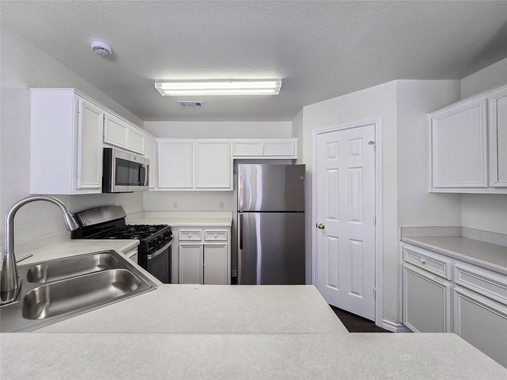 300 Tamara Drive, Unit B Georgetown, TX 78628 - Photo 9 of 16 a kitchen with a refrigerator sink and white cabinets