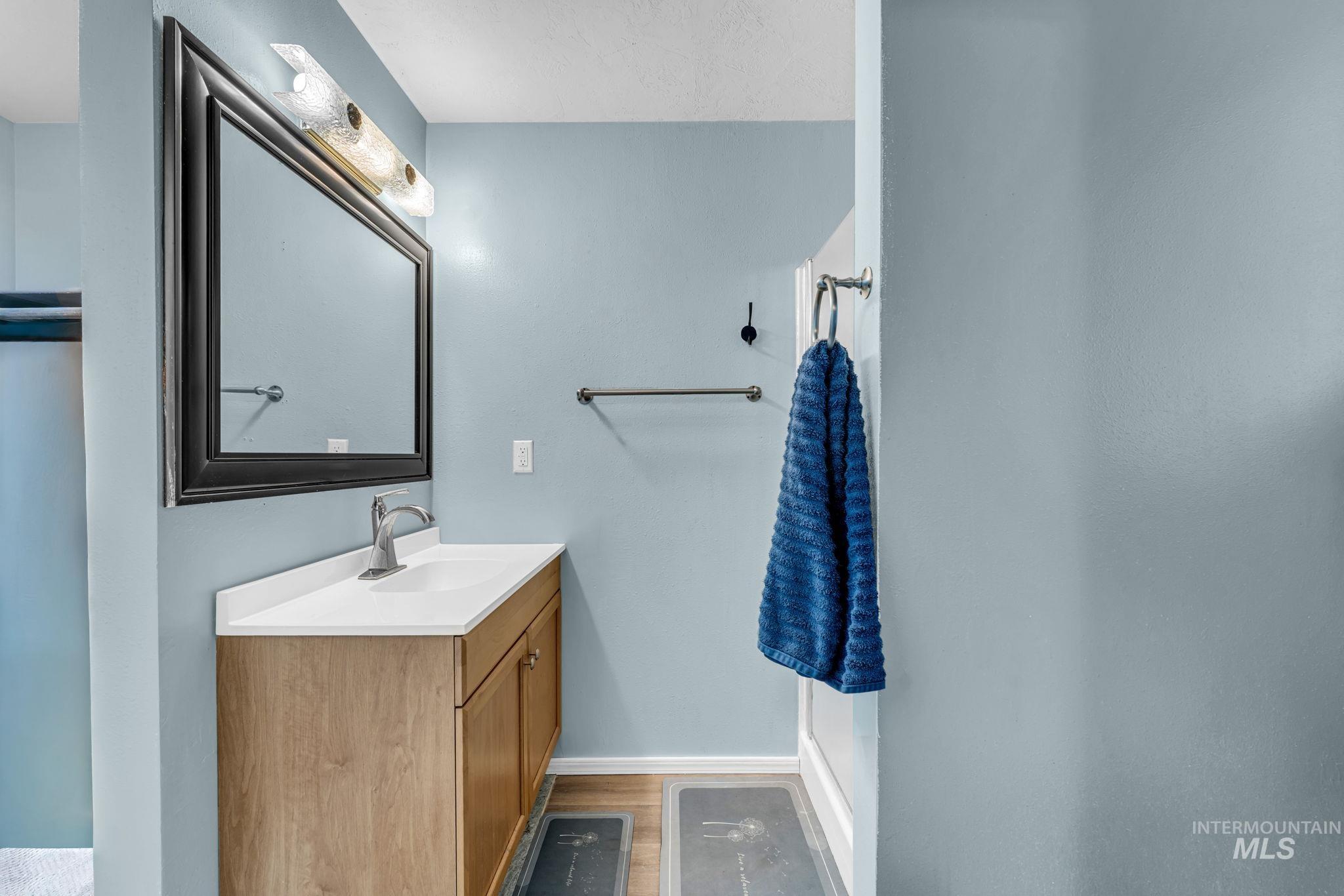 820 Meadows Drive Twin Falls, ID 83301 - Photo 19 of 38 Bathroom featuring a light wood-finish vanity with a white countertop and undermount sink, a large framed mirror, and a toilet