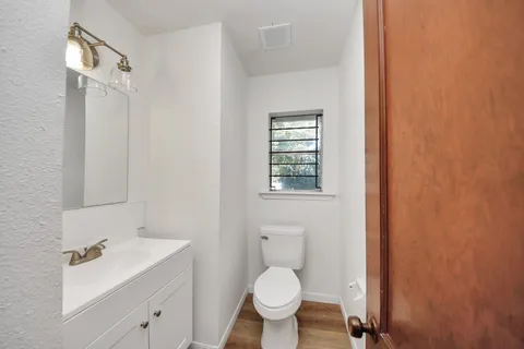 a bathroom with a toilet sink vanity and mirror
