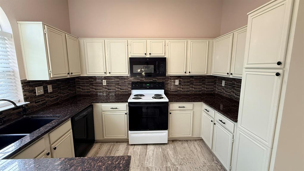 12259 Rim Rock Road Dallas, TX 75253 - Photo 7 of 17 Kitchen with black appliances, tasteful backsplash, dark stone countertops, and white cabinets