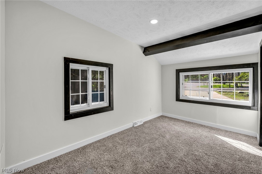 7339 River Road Olmsted Falls, OH 44138 - Photo 22 of 45 Interior room featuring vaulted ceiling, exposed dark wood beam, recessed lighting, two windows with dark trim, and plush carpet flooring
