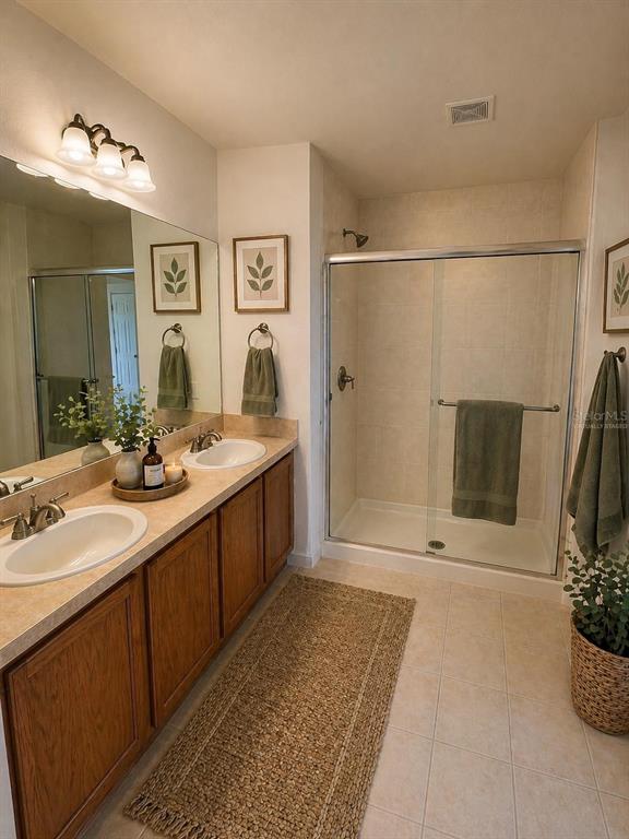 2543 Old Kent Circle Kissimmee, FL 34758 - Photo 14 of 41 a bathroom with a double vanity sink a large mirror a shower and a bathtub