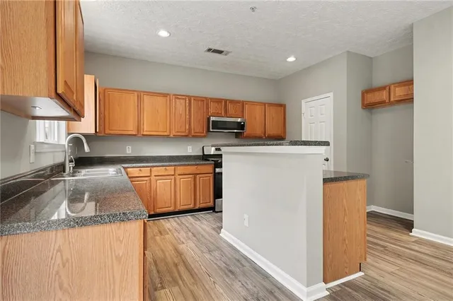 a kitchen with granite countertop wooden floors and white stainless steel appliances