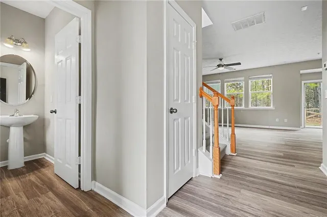 a view of a hallway with wooden floor and a bathroom