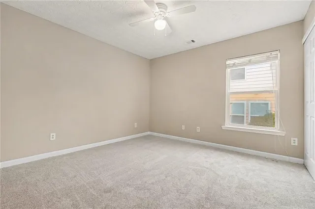 an empty room with a window and a fan