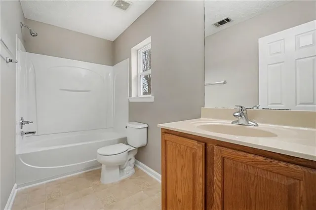 a bathroom with a granite countertop sink a toilet and a bathtub
