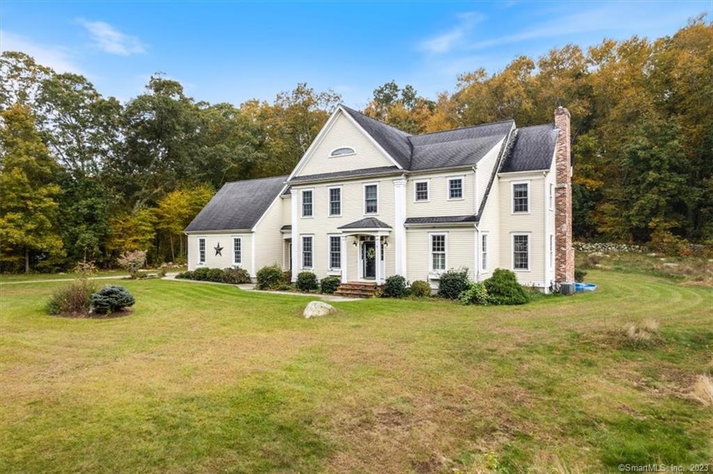 a view of a big house with a big yard and large trees
