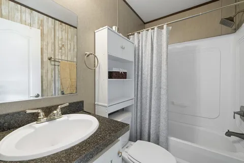 a bathroom with a granite countertop sink toilet and shower