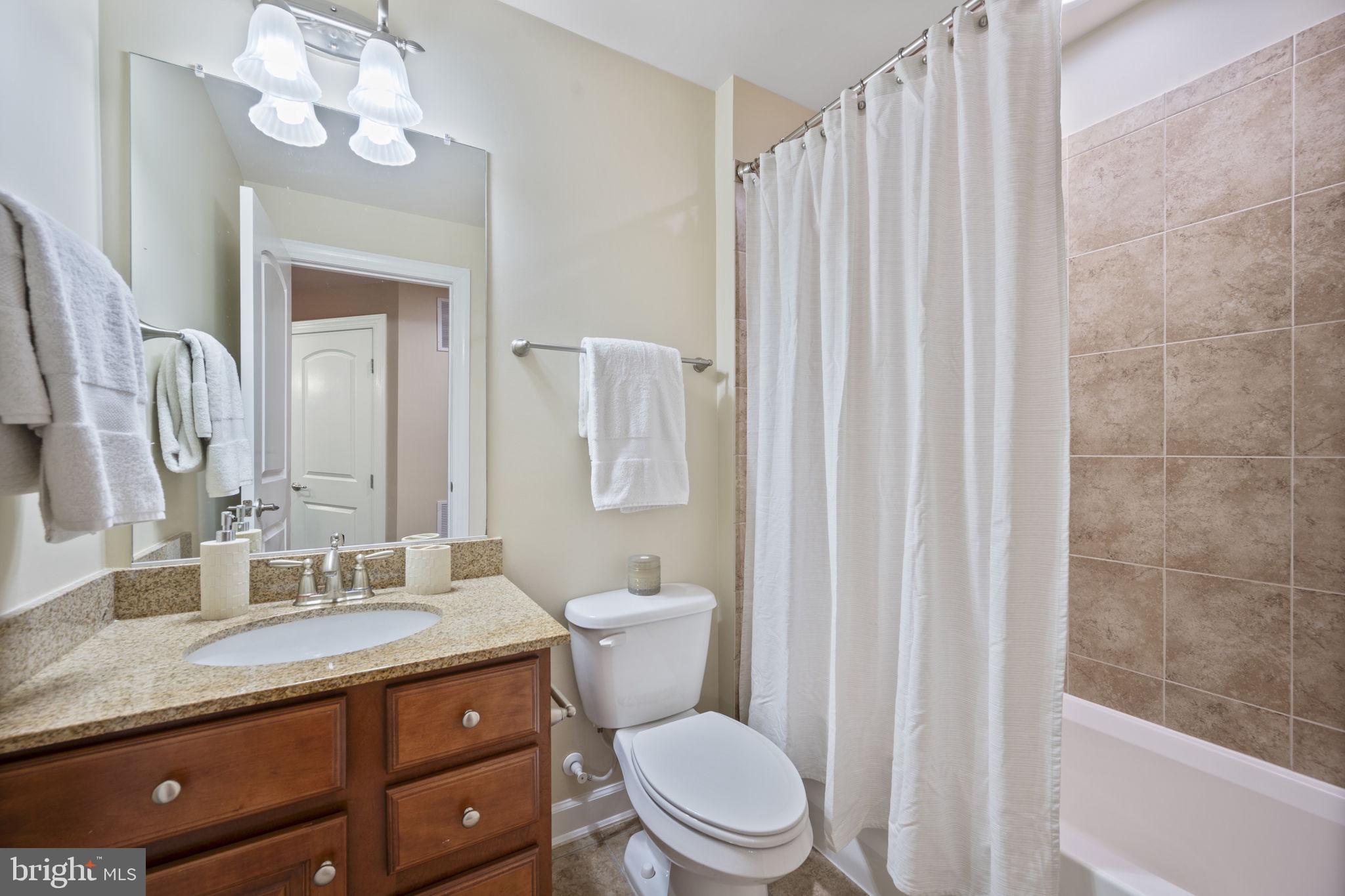 8976 Tawes Street Fulton, MD 20759 - Photo 14 of 65 a bathroom with a granite countertop sink a toilet and a mirror