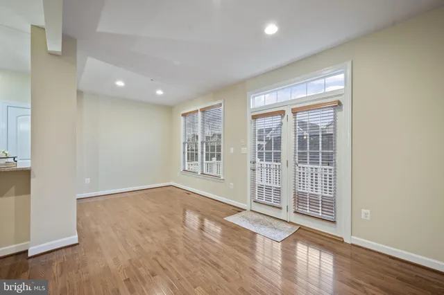 a view of an empty room with wooden floor fireplace and a window