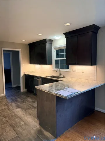 a kitchen with kitchen island granite countertop a sink and a stove top oven with wooden floor