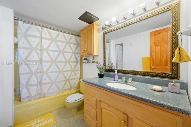a bathroom with a granite countertop sink toilet a mirror and shower