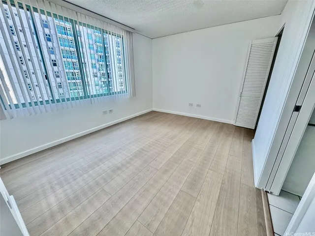 a view of an empty room with closet and a window