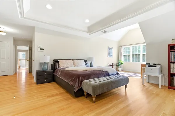 a spacious bedroom with a bed and wooden floor