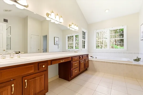 a spacious bathroom with a granite countertop bathtub sink and mirror