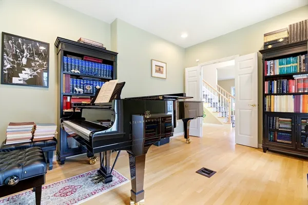 a living room with furniture a piano and a bookshelf
