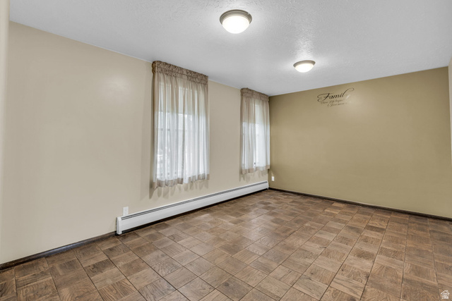 10705 Green Ridge Drive Sandy, UT 84070 - Photo 23 of 55 Empty room featuring a baseboard heating unit, parquet flooring, and a textured ceiling
