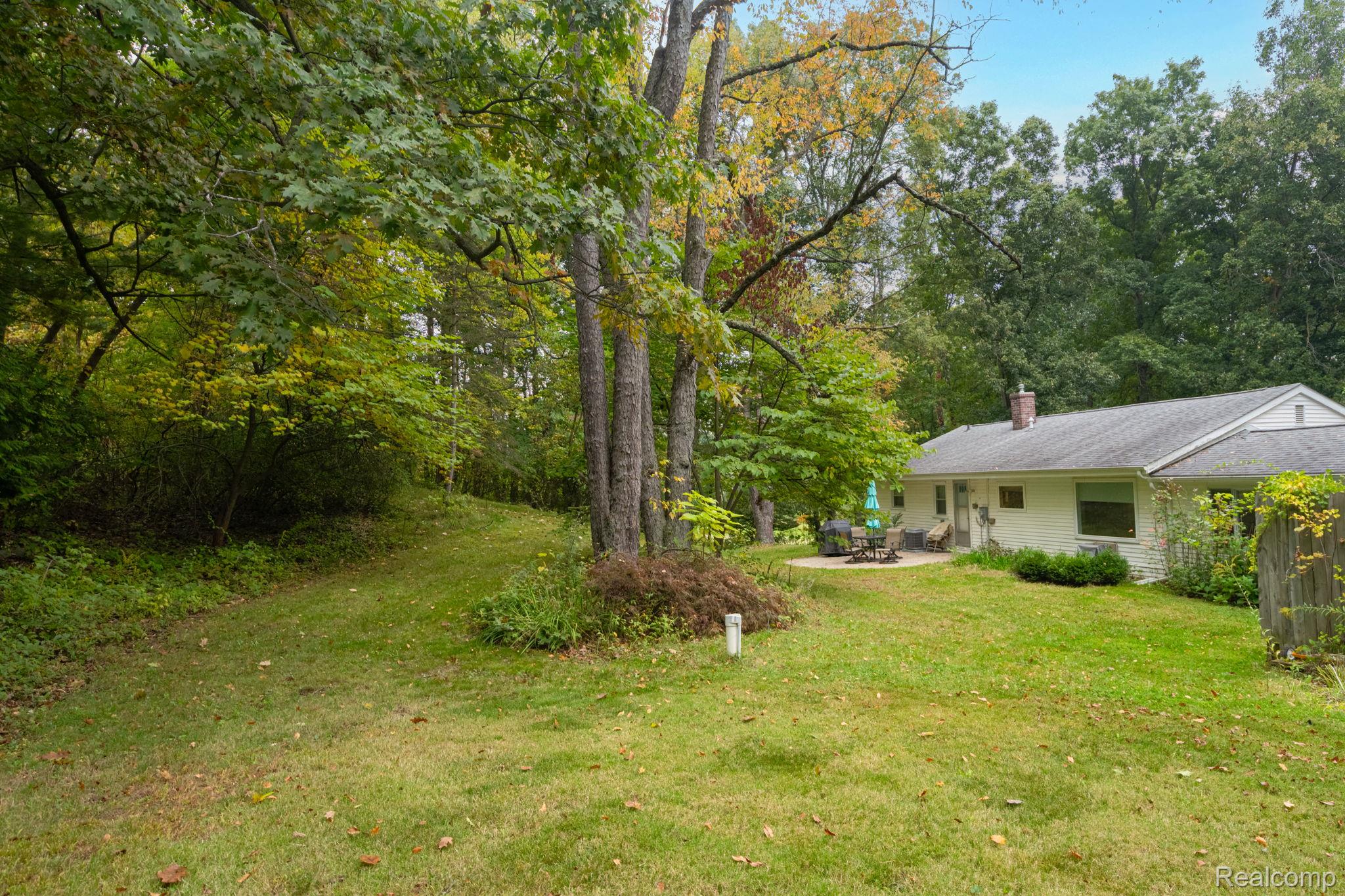 1775 Porter Road White Lake, MI 48383 - Photo 7 of 33 Expansive green lawn with mature trees and a rear patio