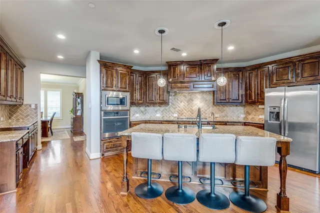 a kitchen with stainless steel appliances granite countertop a sink a stove and a wooden cabinets