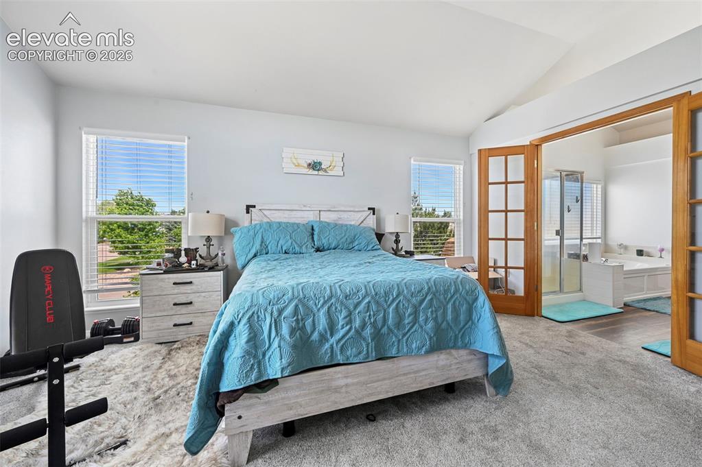 8347 Tibbs Road Peyton, CO 80831 - Photo 20 of 39 Spacious bedroom featuring vaulted ceilings, two large windows with horizontal blinds, and carpet flooring