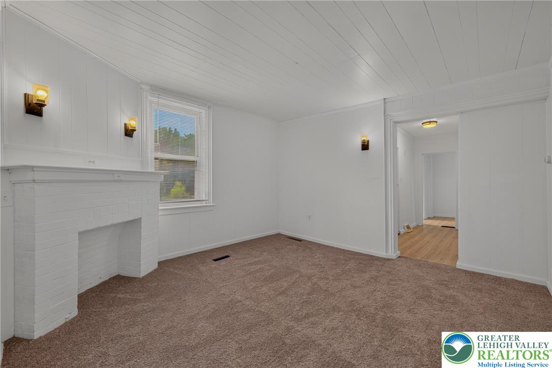 313 Main Street Slatington, PA 18080 - Photo 13 of 73 A well-lit room featuring a classic brick fireplace and rich carpet flooring.