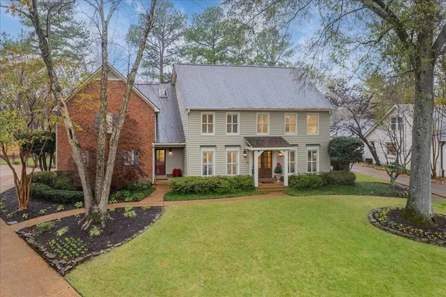 a view of a big house with a big yard and large trees