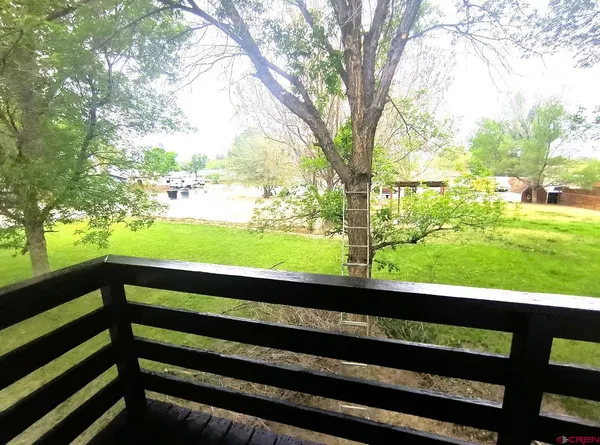 a view of house with wooden deck and trees in the background