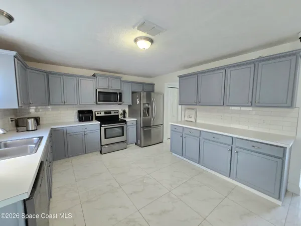 a kitchen with granite countertop a refrigerator and a stove top oven
