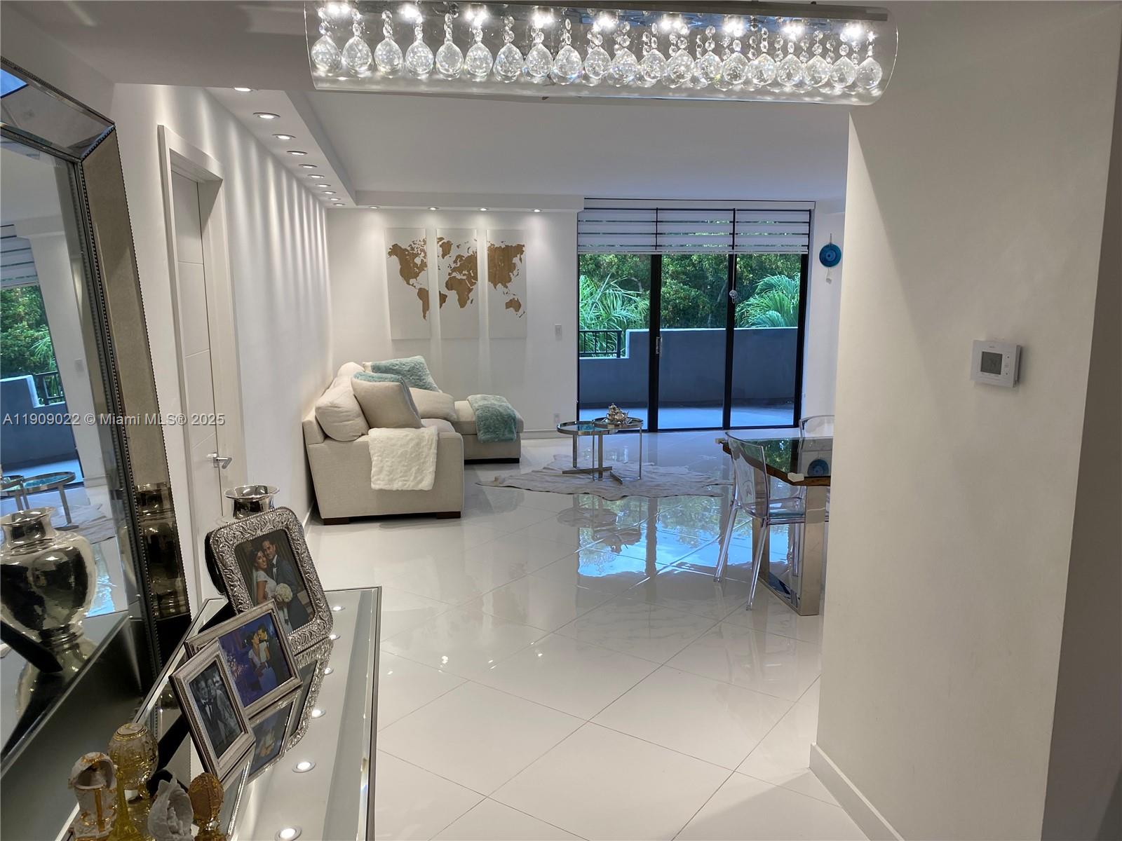 121 Crandon Boulevard, Unit 351 Key Biscayne, FL 33149 - Photo 6 of 15 a living room with furniture a chandelier and a large window