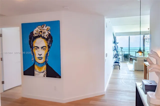 a hallway with painting on the wall and a potted plant