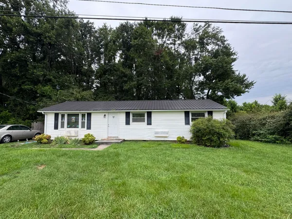 a front view of a house with a yard and trees