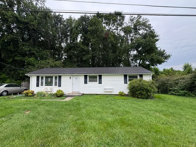 a front view of a house with a yard and trees