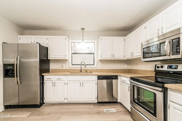 a kitchen with cabinets stainless steel appliances and a counter space
