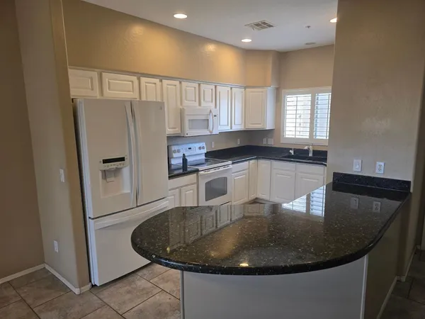 a kitchen with stainless steel appliances granite countertop a sink a refrigerator and a granite counter tops