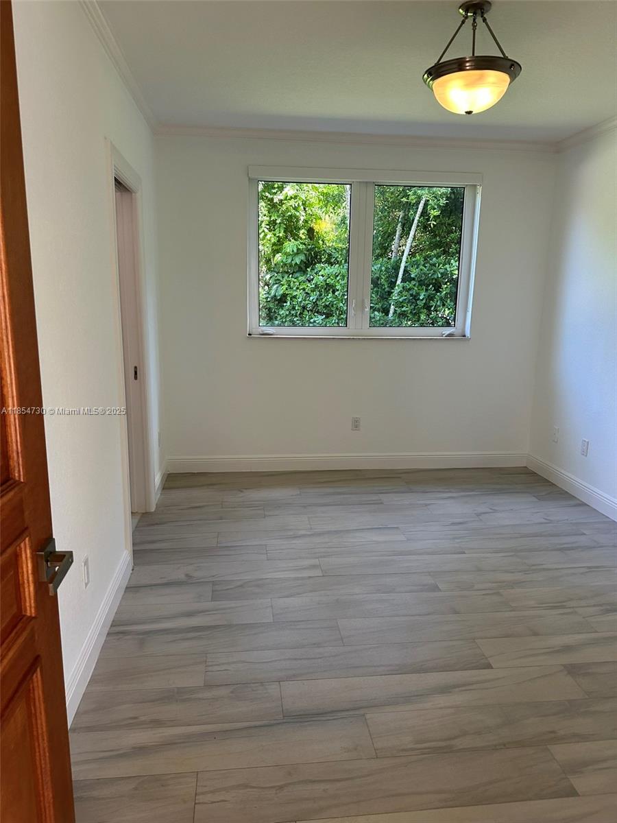 10600 Southwest 69th Avenue Pinecrest, FL 33156 - Photo 32 of 55 an empty room with wooden floor and windows