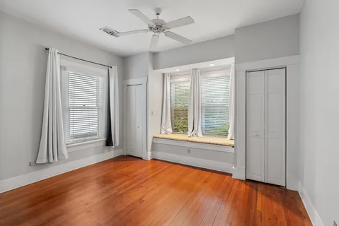 a view of an empty room with a window and wooden floor