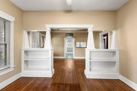 a view of a hallway with wooden floor and cabinet