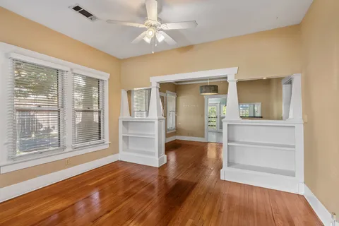 a view of empty room with wooden floor and fan