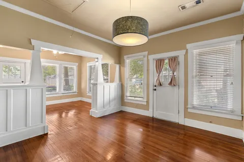 a view of an empty room with wooden floor and a window