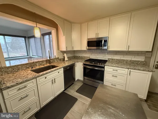a kitchen with granite countertop white cabinets and white appliances