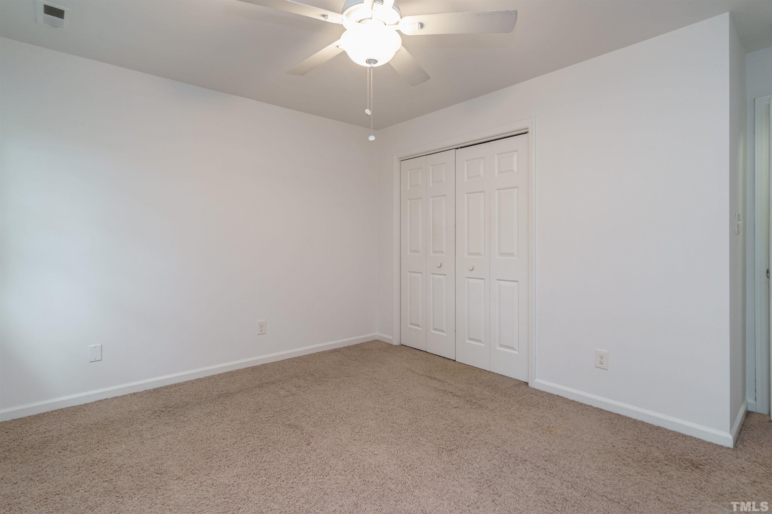 2502 Noble Road Raleigh, NC 27608 - Photo 16 of 19 an empty room with a chandelier fan and windows